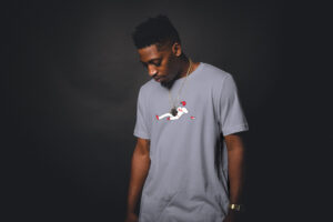 man in dark room wearing grey philly slide tee shirt